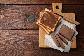 Sandwiches with chocolate butter and knife on wooden table, top view. Space for text