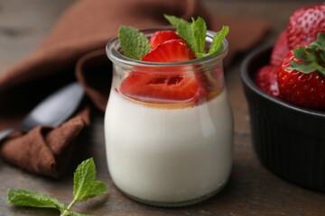 Tasty panna cotta with caramel, strawberries and mint on wooden table, closeup