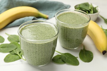 Tasty spinach smoothie and ingredients on white table, closeup