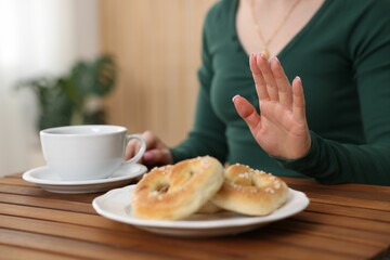 Gluten free diet. Woman refusing from pretzels indoors, closeup