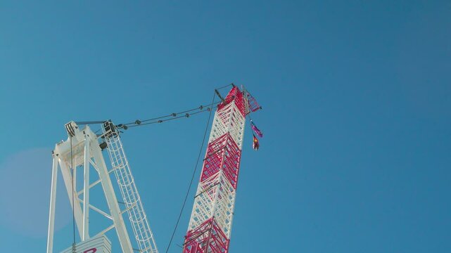 Low-angle view of the Aboriginal flag flying atop a steel crane against skies at a construction site
