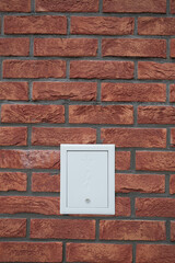 Brick wall with electrical panel Neutral white cover Close up shows texture Red brick and grey mortar Indoor or outdoor minimal