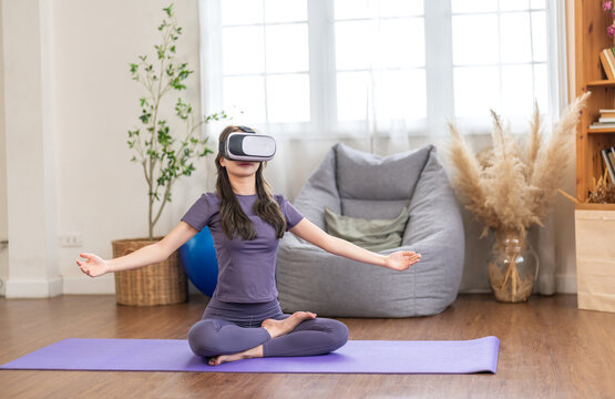 Young woman engaging in virtual reality workout session in living room, she wearing VR headset while performing yoga, modern technology with physical fitness, digital fitness trends at home