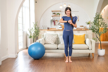 Fitness woman holding yoga mat and look at smartwatch checking heart rate, calories burned, tech in home gym, fitness, health tracking, self care, technology and healthy living, digital wellness