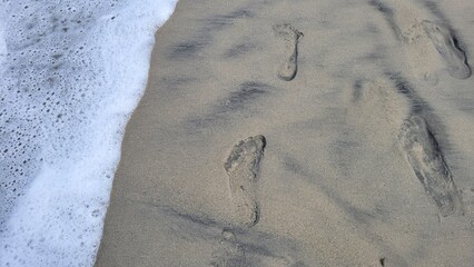 Footprints in the Sand Being Washed Away by Ocean Waves