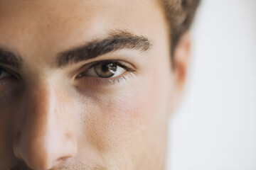 Primer plano de los ojos y cejas de un hombre de unos 20 años, de apariencia ordenada y pulcra, estilo publicitario, con piel bronceada.
