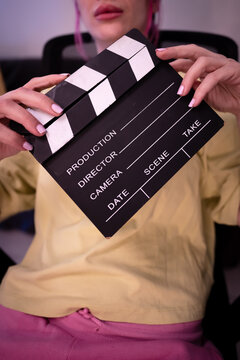 Close-up of a person holding a clapperboard in a creative setting, symbolizing filmmaking, entertainment, and production themes, featuring vibrant colors and modern cinematic vibes.
