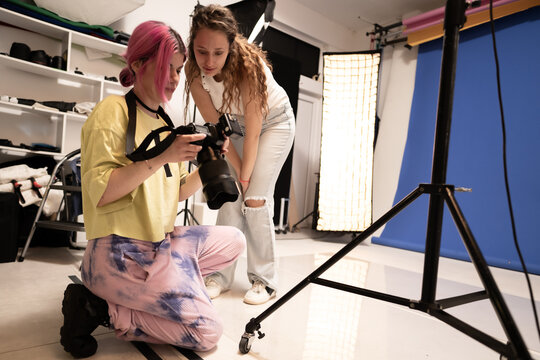 Two women reviewing photos on a professional camera in a modern photography studio setup