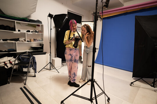 Professional photographer discussing shots with a model during a photoshoot in a studio environment