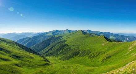 Obraz premium Panoramic view of lush green mountain ranges under a vibrant blue sky