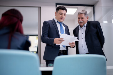 Business professionals discussing documents during a meeting in a modern office setting.