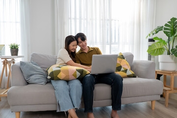 Obraz premium Asian young couple using laptop computer in living room at home.