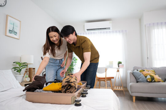 Asian young beautiful couple preparing clothes and packing suitcase.
