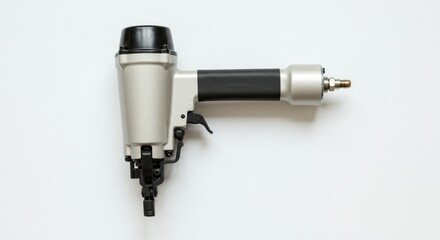 A pneumatic nail gun, light gray and black, sits on a white background