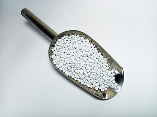 White plastic masterbatch, polymer carries colorful pigments with small scoops poured into a white...