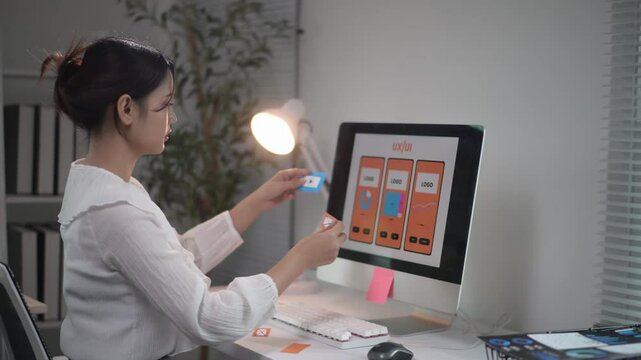 Asian web designer working using sticky notes on computer screen