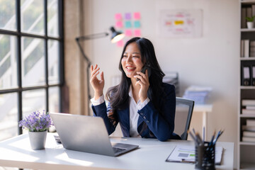 A woman is talking on her cell phone while sitting at a desk