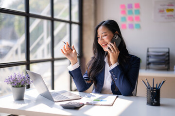 A woman is talking on her cell phone while sitting at a desk