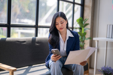A woman is sitting on a couch and looking at her phone