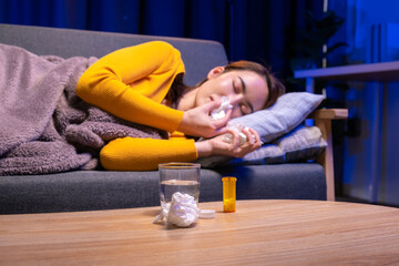 A woman is laying on a couch with a glass of water