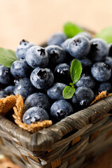 Ripe blueberries in wicker basket on wooden table.