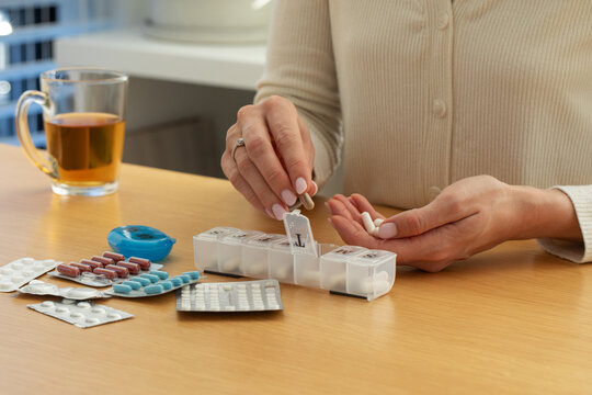 Daily medication organization with pill box and tablets on wooden table. Health care