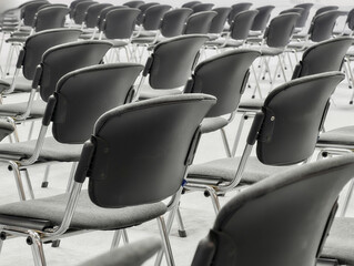 Rows of empty black chairs arranged neatly in a spacious room ready for an event or meeting