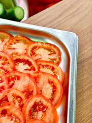 Freshly sliced tomatoes arranged on a stainless steel tray ready for a delicious meal in a cozy...