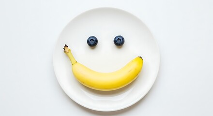 Smiley face made with banana and blueberries on white plate, healthy breakfast concept