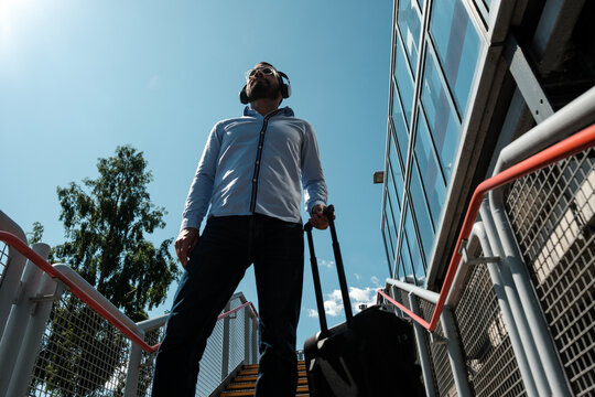 Businessman listening to music while walking up stairs at train station - Powered by Adobe