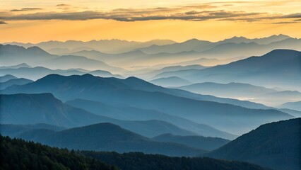 Fototapeta premium Majestic mountain range silhouette layered with atmospheric haze during a vibrant golden sunrise sky