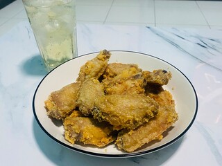 Fried chicken on a table with glasses of liquor and ice soda