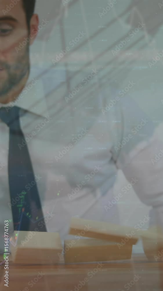 Poster animation of graphs and numbers over caucasian businessman playing with toy blocks falling on table