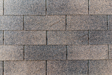 asphalt roof shingles, exhibiting a weathered, granular texture and varying shades of gray and brown, ideal for exterior design and architectural themes.