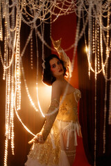 Young Caucasian circus performer or burlesque dancer in golden vintage corset, front view, posing...