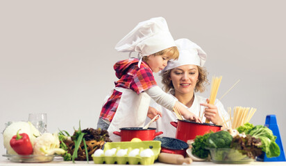 Mother and child cooking together. Kid baby helping mom to cooking in kitchen. Mother and son cooking healthy meal. Child chef with Mother with apron cooking on kitchen. Mom and baby chef.
