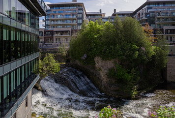 Elora Gorge waterfall on Grand river in the downtown near an old mill, a restaurant and new condo buildings, lilac tree blossom. Urban together with nature. Elora, Ontario, Canada