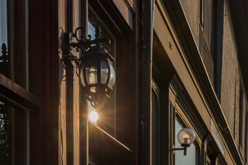 Vintage still life - old street lamp hanging on a window with sun rays inside. Macro with dramatic blurred background.