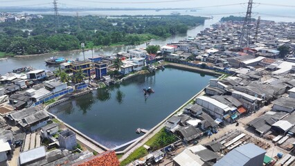 View from above of an excavator dredging a lake on the riverbank in North Jakarta