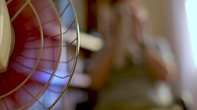 Blurry Person Cooling off With a Fan on a Hot Day