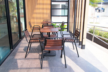Interior table and chairs outdoors in street cafe on brown cement floor background. Lifestyle, leisure, drinking, eating out concept, romantic. Modern cafe in loft style, black table set for coffee.