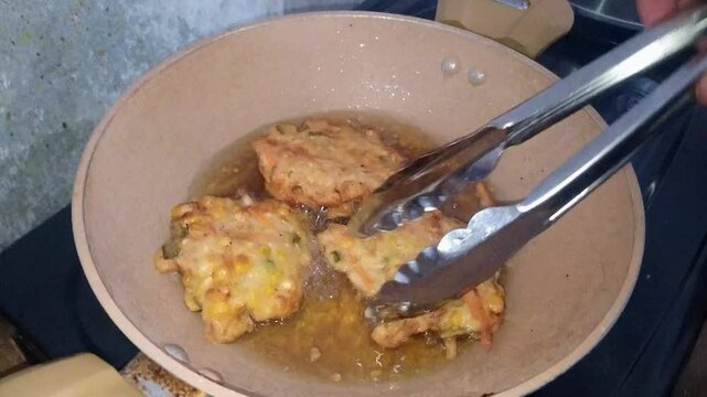 Close-up of bakwan cooked in boiling oil. Bakwan is a traditional Indonesian dish, a mixture of wheat flour, sliced carrots, cabbage, and corn.