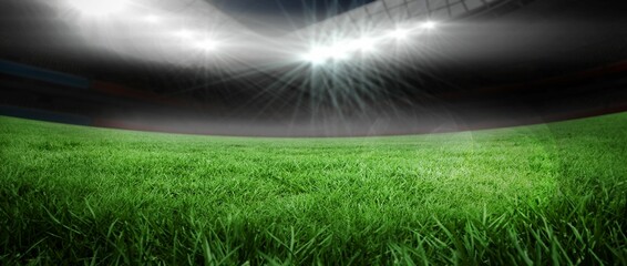 Green grass pitch is stretching in flat design stadium with overhead floodlights and shadowed seats