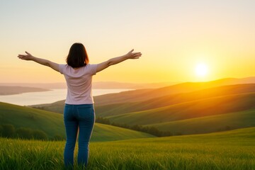 Woman enjoying sunrise with open arms on grassy hill with scenic valley and sunlight in peaceful morning lifestyle concept background.