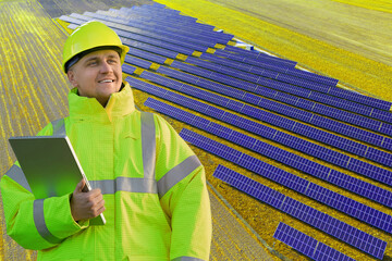 Smiling engineer in yellow jacket next to solar panel array