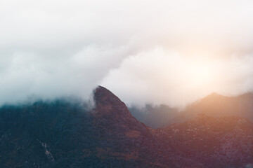 Fog covering mountain peaks above green fjord bay
