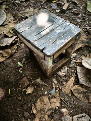 A weathered wooden bench, showing signs of aging, placed on the ground
