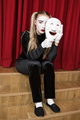The focus is on a mime artist with a mask in his hand.