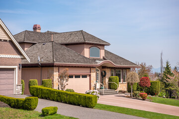 Fototapeta premium Two story stucco luxury house with nice spring blossom landscape in Vancouver, Canada, North America. Day time on June 2025.