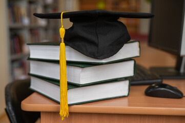 Graduation cap on a stack of books in the library. 